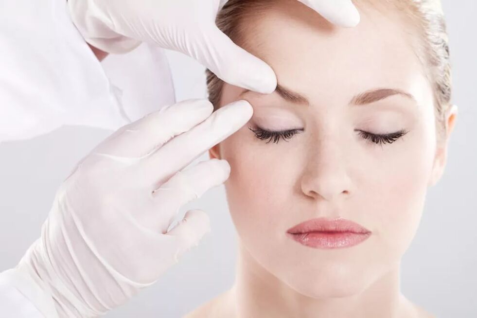 Der Kosmetiker untersucht die Haut um die Augen um die Augen