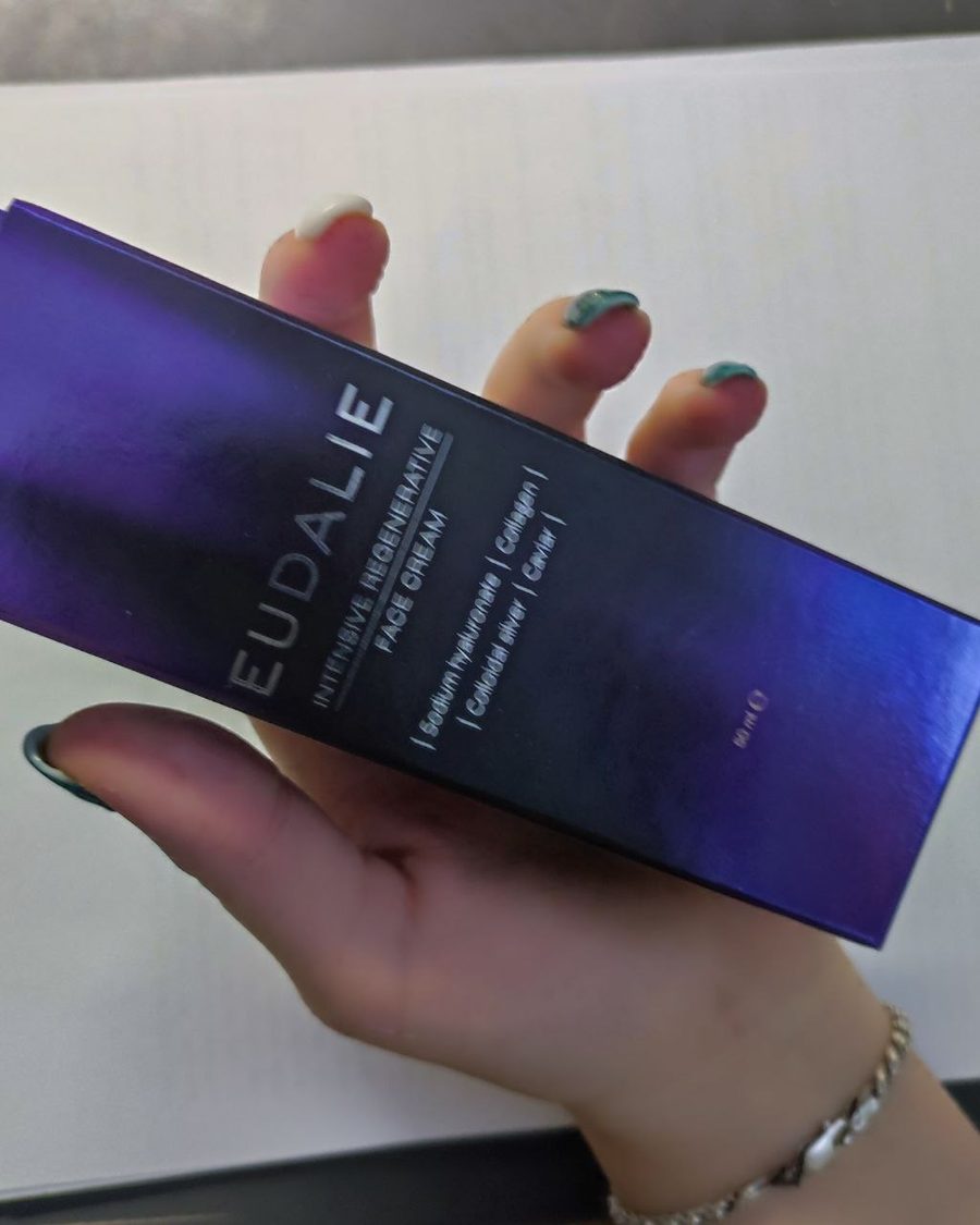 Rokā turēta violeta Eudalie Intensive Regenerative Face Cream kastīte